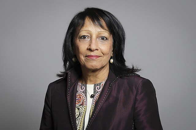 A photo of Baroness Kishwer Falkner in a brown jacket against a grey gradient background