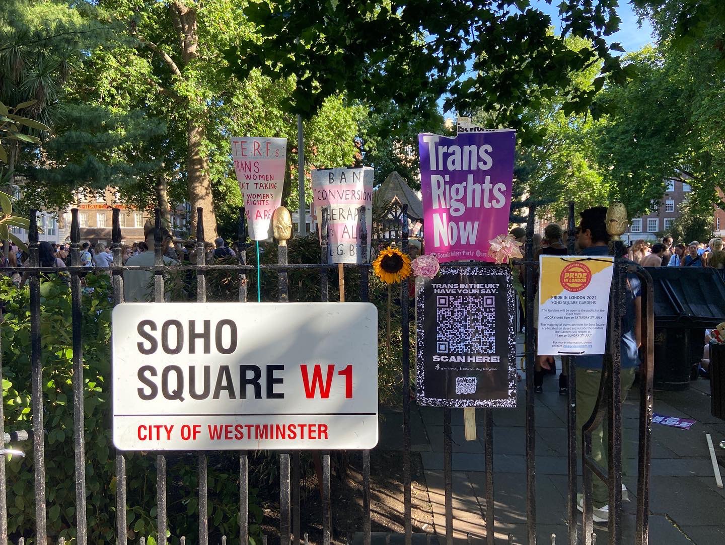Soho Square sign surrounded by Trans Pride London signs reaching things like "Trans Rights Now" from a trans rights protest in Westminster