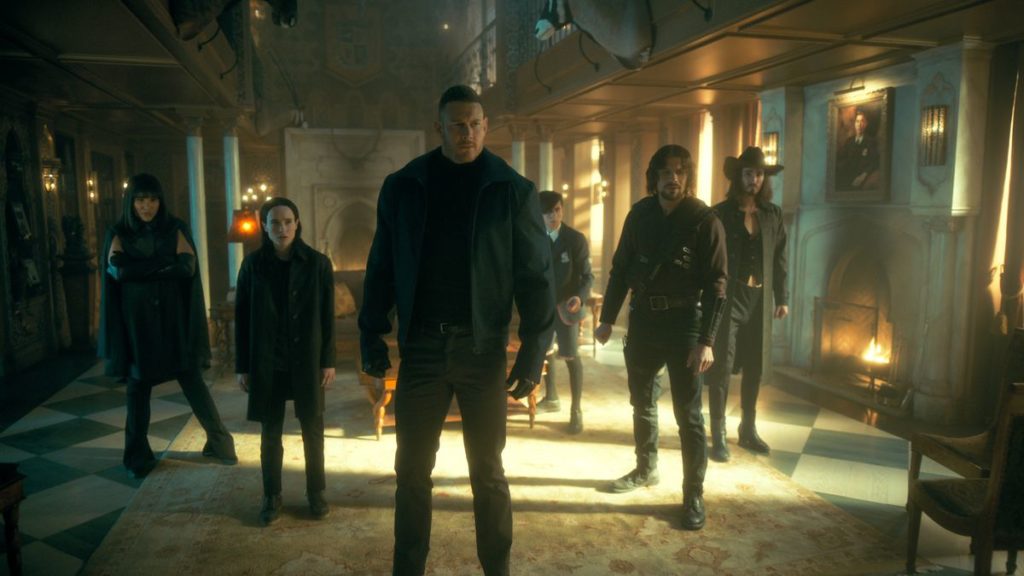 A wide shot of all of the siblings from The Umbrella Academy standing in The (now) Sparrow Academy from The Umbrella Academy Season 3