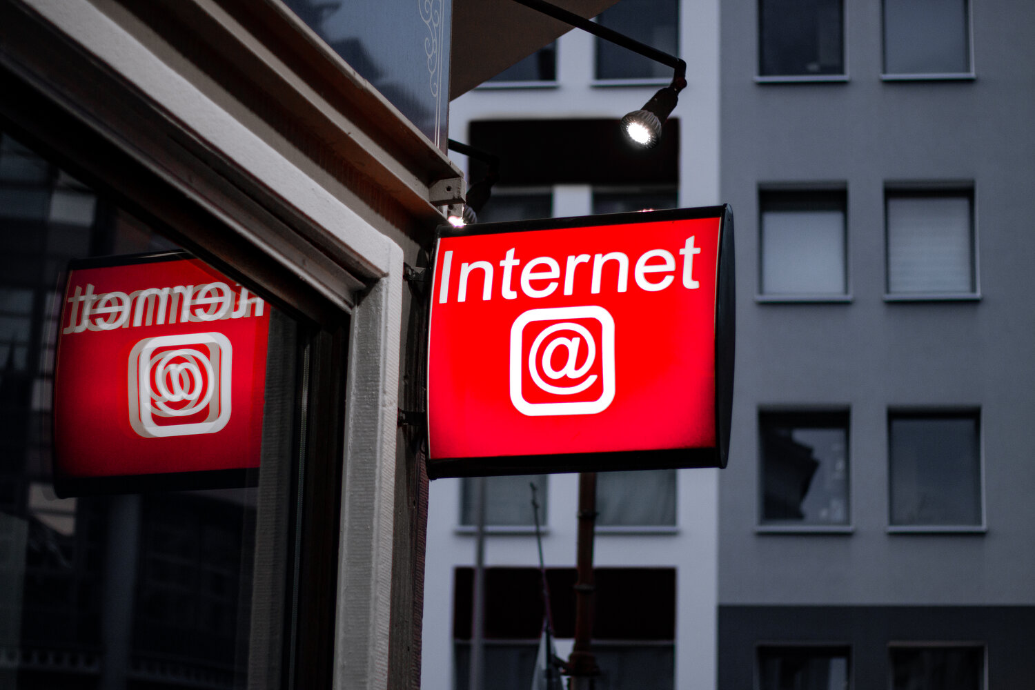 #DropKiwiFarms: a grey building with a large red sign reading "internet" and displaying an "@" symbol. Meant to represent a generic internet café.