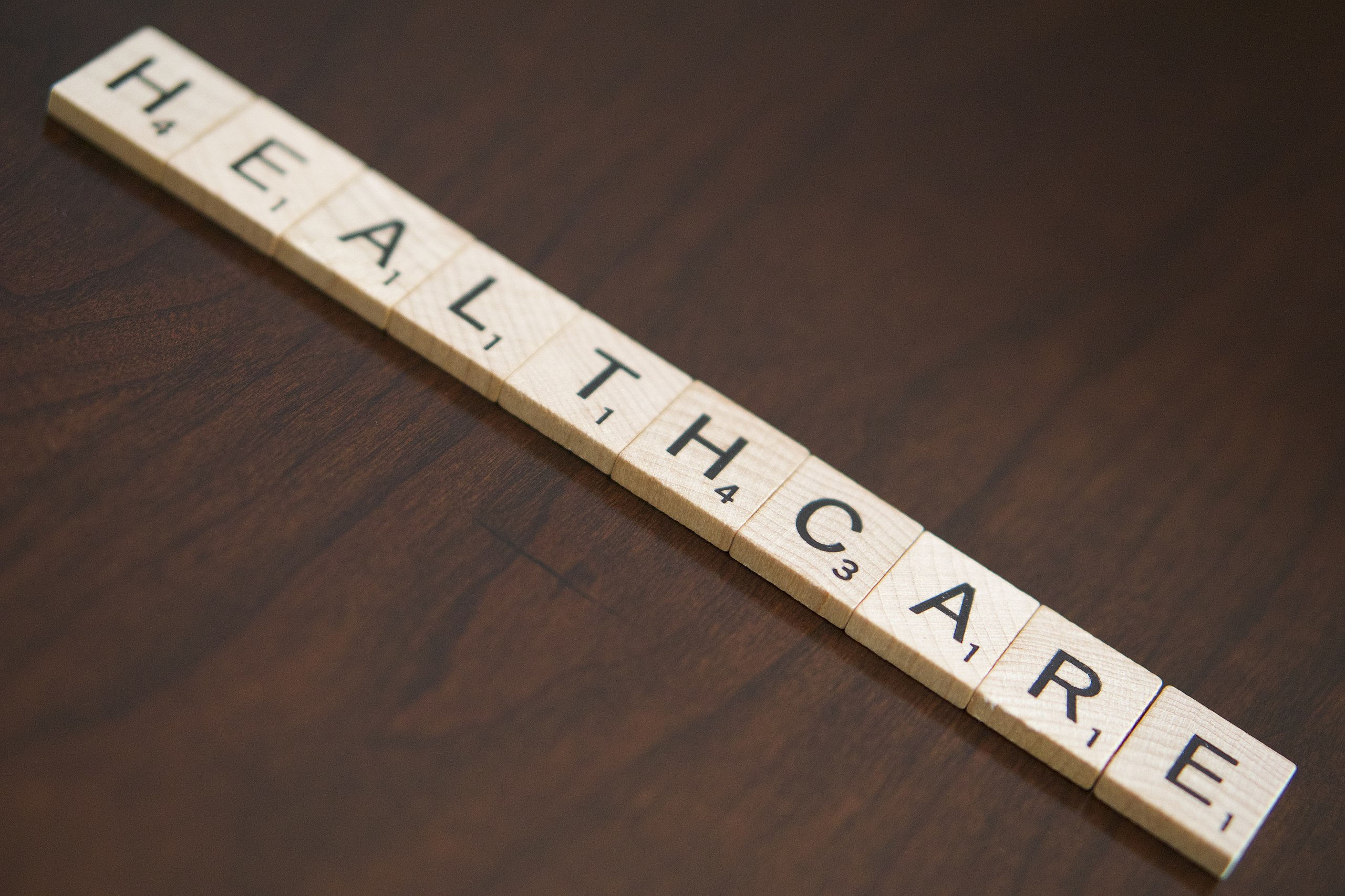 Healthcare spelled out in scrabble tiles. To represent trans healthcare on the NHS.