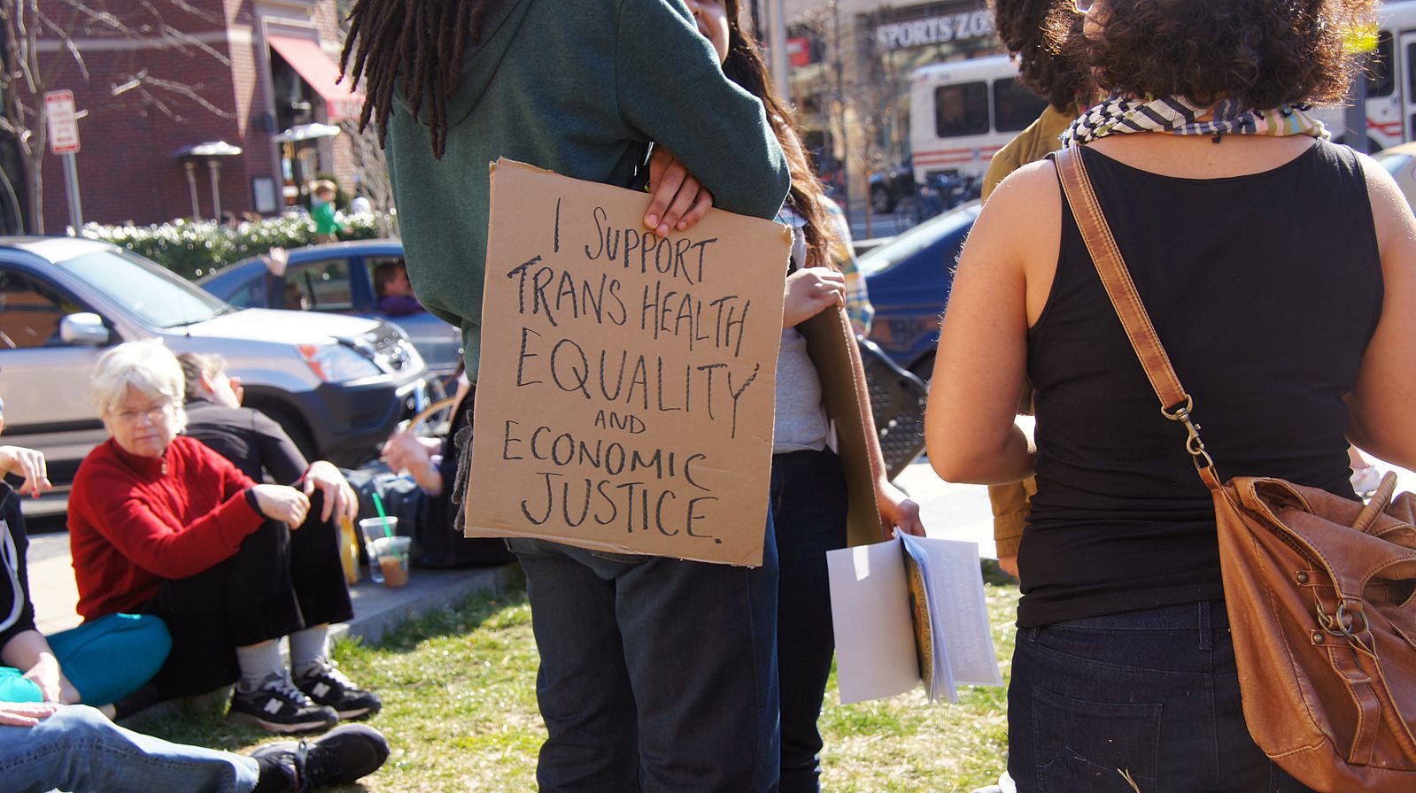 A photo from a rally in 2013; someone holds a sign reading "i support trans health equality and economic justice" photo by Ted Eytan source: Wikime...