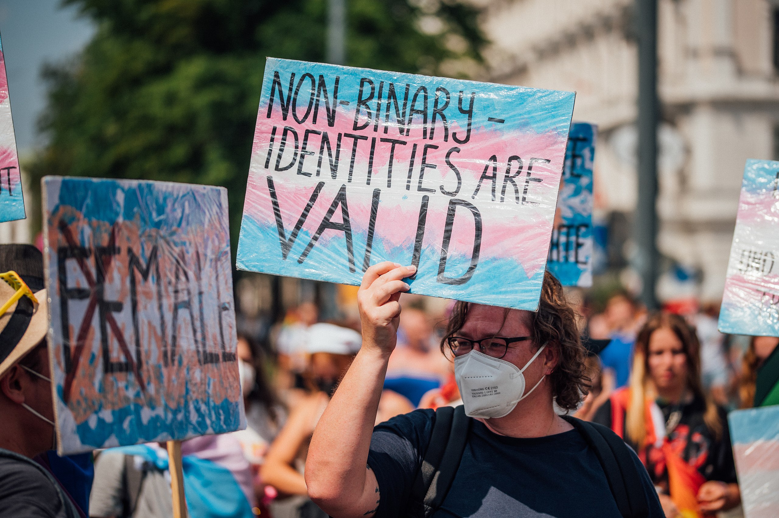 Photo of a person at Pride holding a transgender flag sign which reads "non-binary identities are valid" which Ryan Castellucci's case is fighting ...