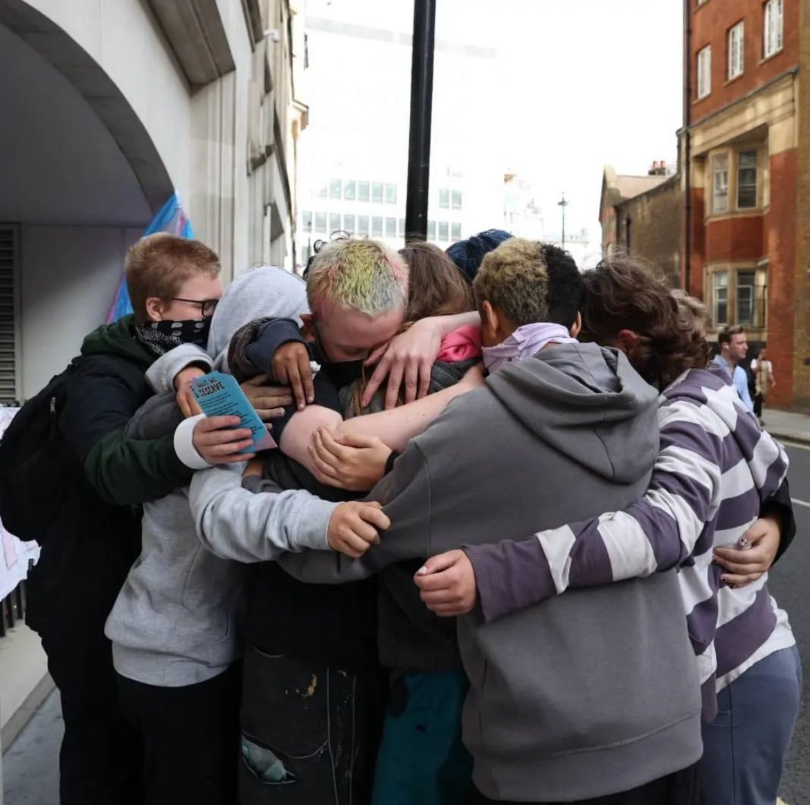 A group of trans youth hug each other moments after one youth had scaled the Department For Education to retrieve a banner. The Trans Kids Deserve ...