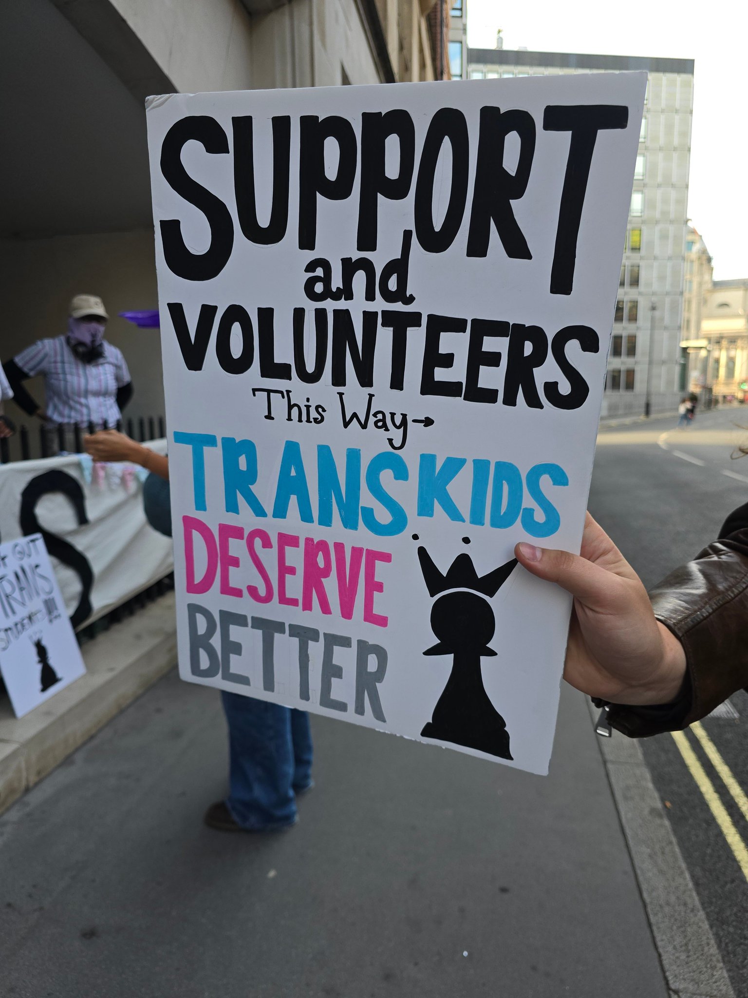 A sign reading "Support and volunteers this way. Trans Kids Deserve Better" Photo credit: What The Trans