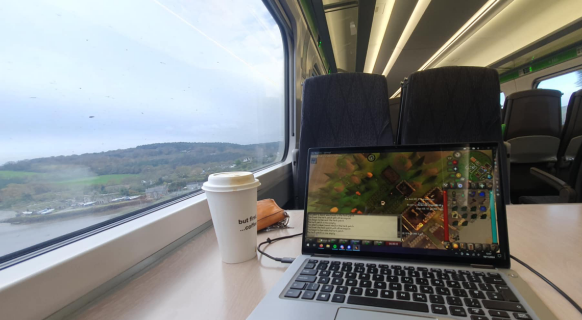 A photo of my laptop on a train with a view of the countryside out of the window. Taken moments before fighting a racist.