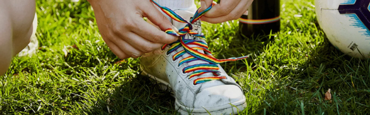 A photo of someone's shoe with rainbow laces that are in the process of being tied. Photocredit: Stonewall UK