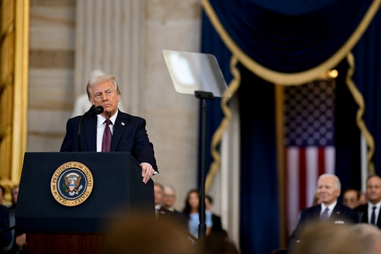 Official White House Photo of Donald Trump at his inauguration as president. He is stood in front of a lectern with the presidential seal and a Uni...
