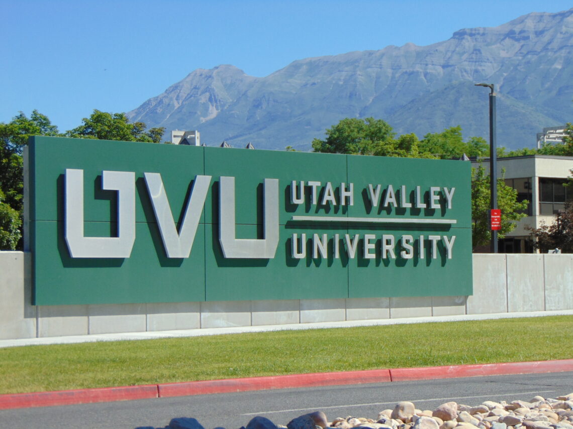 A large green sign reading "UVU Utah Valley University" at the entrance of the site where Charlie Kirk was murdered.