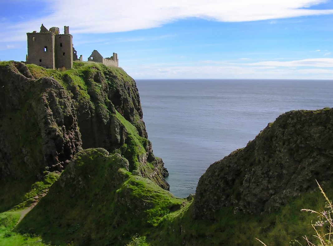 An image of Dunnottar Castle in Scotland. A coastal castle on the very edge of a cliff.