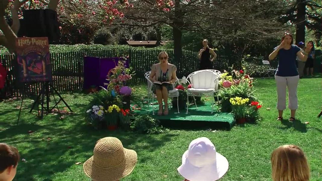 A wide shot of JK Rowling reading from The Sorcerer's Stone in The White House Gardens
