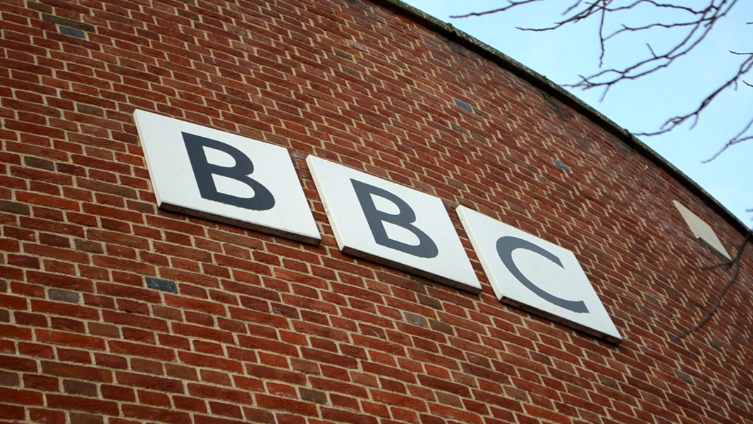 The BBC logo on a curved red-brick wall.