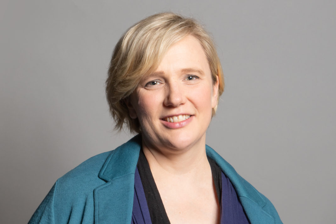 Official press portrait for Stella Creasy MP. The full image also shows her child in a lil papoose kinda thing. Its cropped out of this one because wider images work better than taller for this purpose but I wanted to put it in the alt text because she's a little bit of a badass and this is my salute to that.