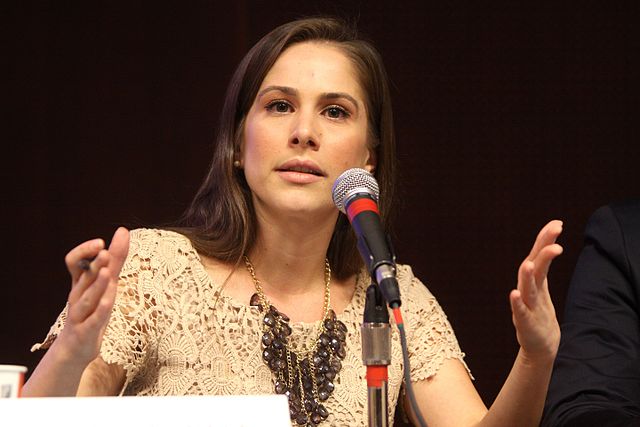 A picture of Ana Kasparian speaking at an event and gesturing with her hands