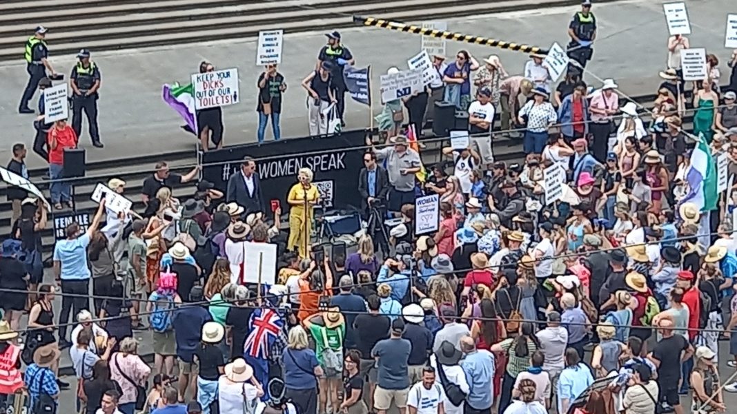 A wide shot of Posie Parker at her rally in Victoria, Australia with a small crowd around her. Photo by @CJMurrumbeena on Twitter.