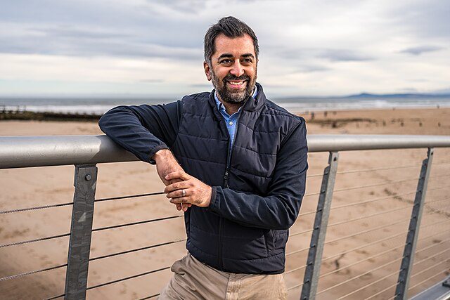 Humza Yousaf leaning on a railing by a beach