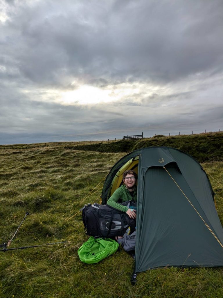 A photo of Jay Hulme with his kit camping on the cliffs